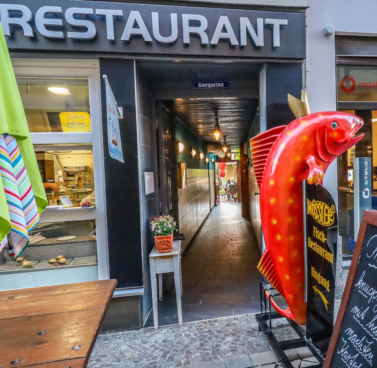 Eingang des Fischrestaurant Hößler mit der roten Fisch-Skulptur und dem Schild „Hössler's Fisch-Restaurant“